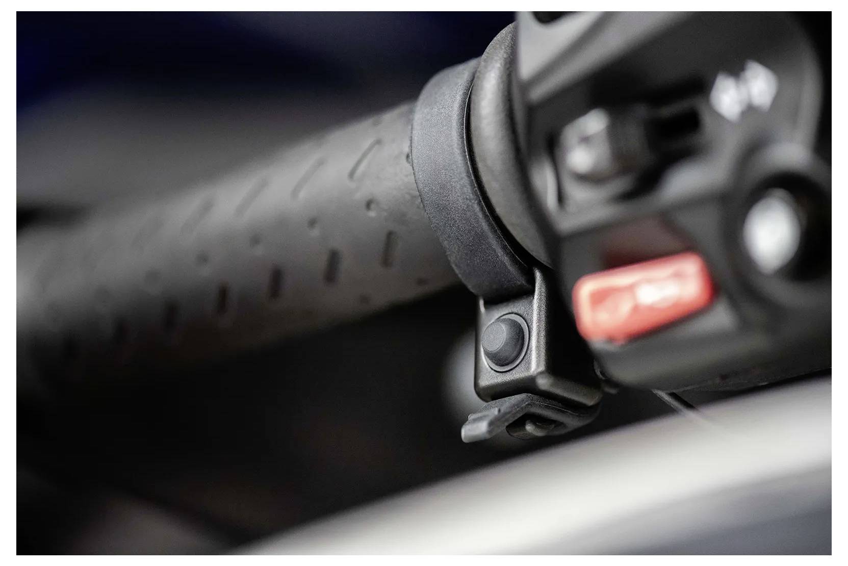 Close-up of a motorcycle handlebar grip with a focus on the textured surface and a control switch, likely used for operating motorcycle functions.