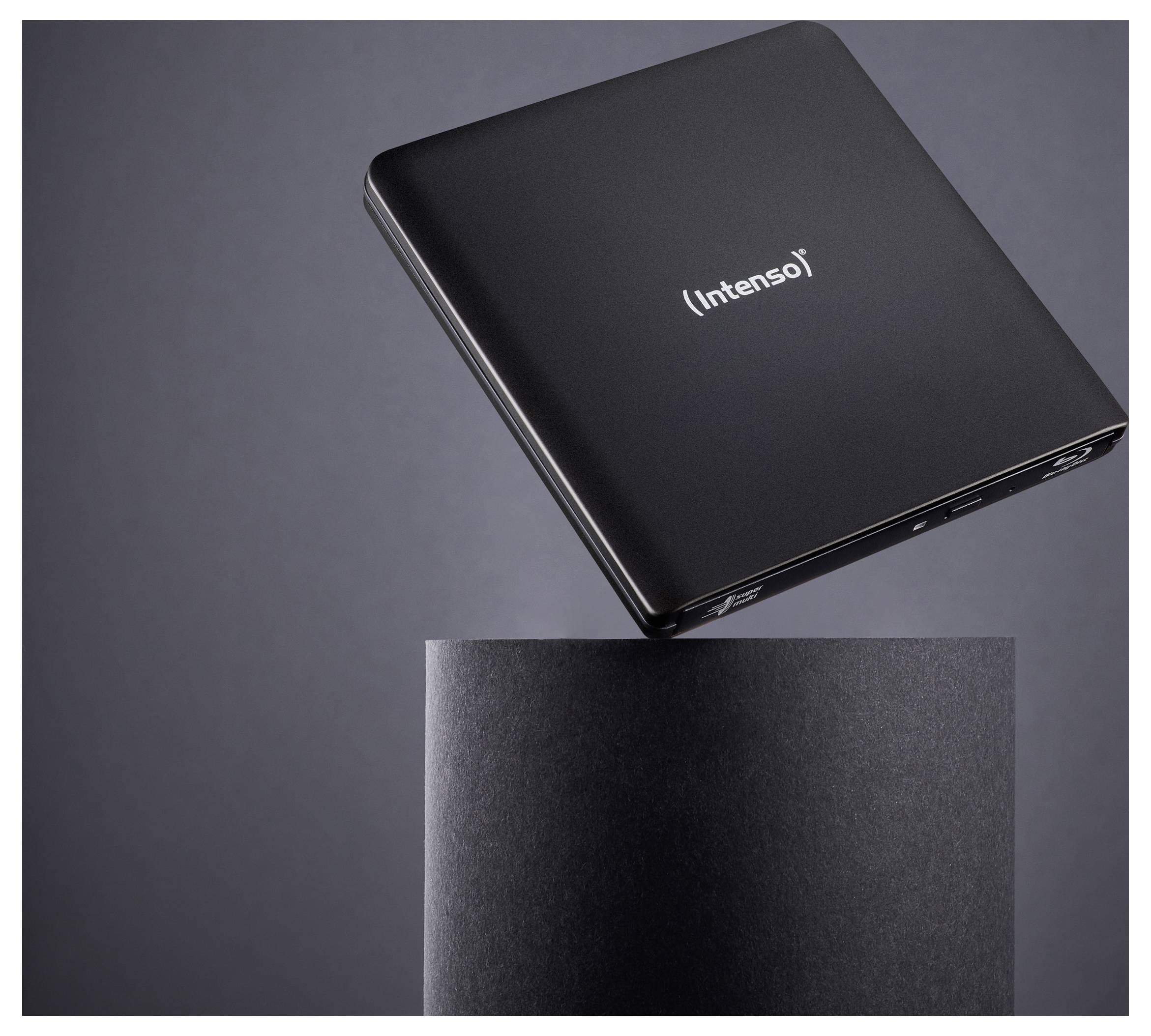 A black Intenso external hard drive hovers over a cylindrical black pedestal, showcasing its sleek and minimalist design.