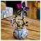 A decorative toy plant featuring a purple and black flower with bell-shaped blooms, set in a pot labeled 'Deadly Night Shade,' with small pumpkins nearby.