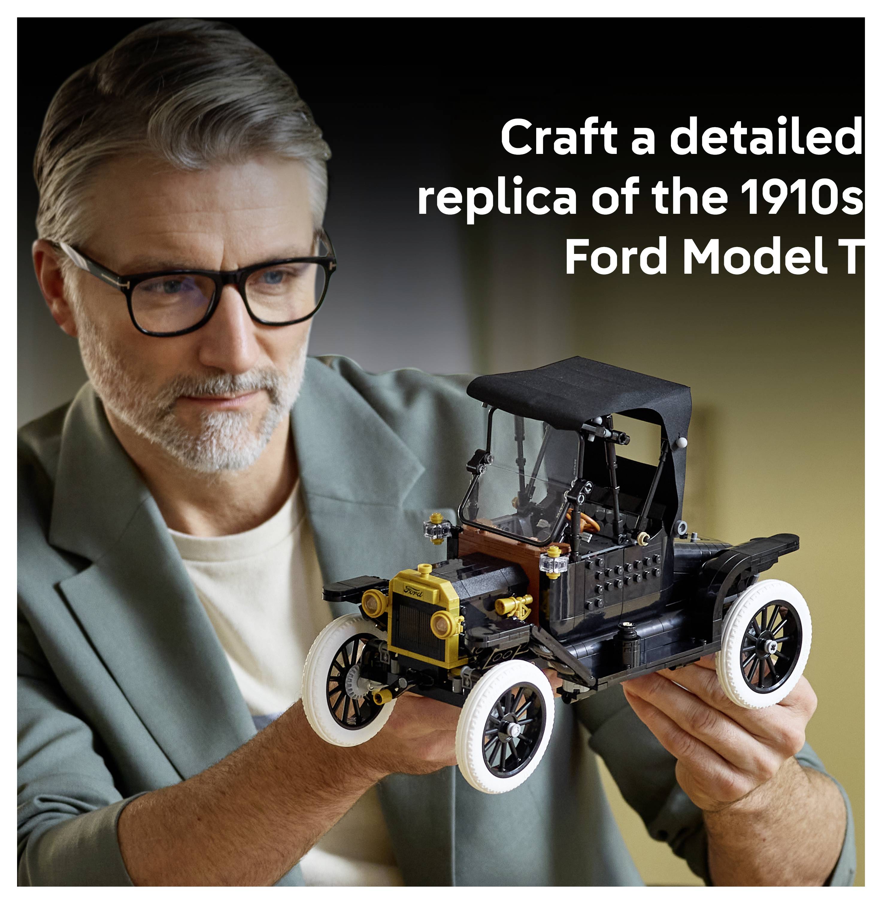 A person holding a detailed model of a 1910s Ford Model T, showcasing its intricate design and craftsmanship with a focus on wheels and body.