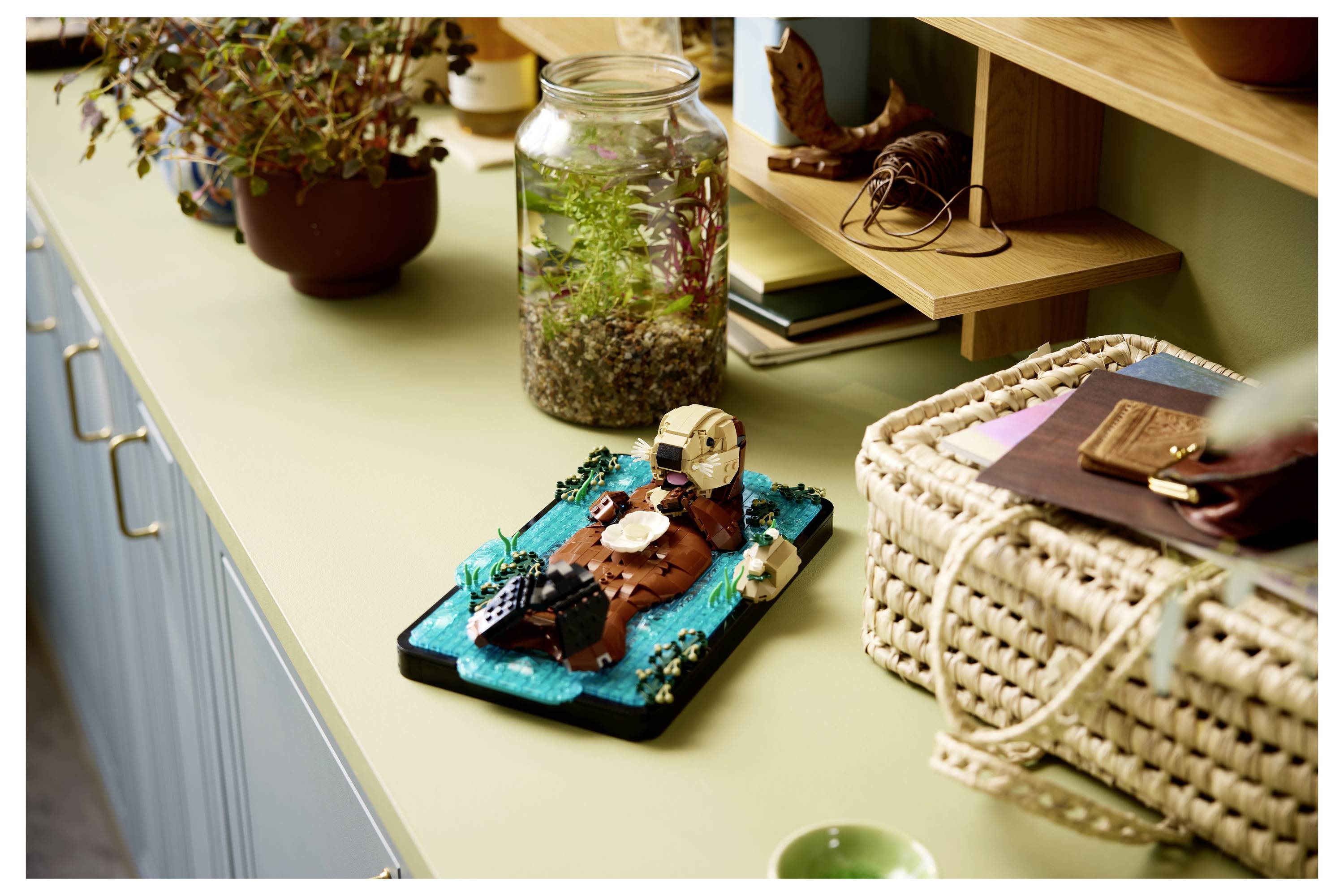 A miniature diorama on a countertop depicts a small farm scene with a barn, silo, and fenced area, surrounded by potted plants and jars.