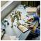 A person assembles a green and white robot model at a desk with tools and parts nearby, showcasing creativity and focus.