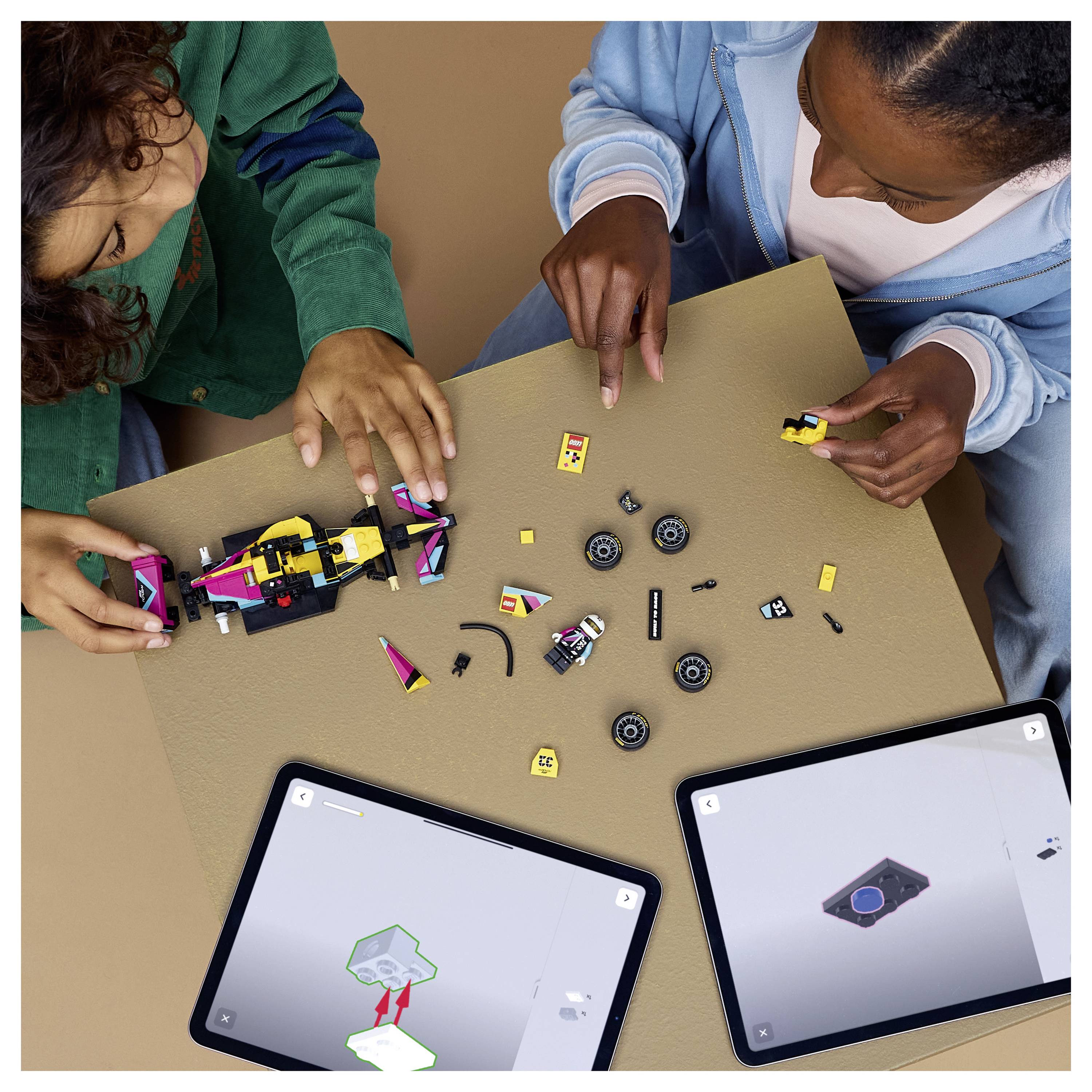 People assemble LEGO pieces on table, referencing instructions on two tablets.