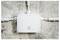 White electrical junction box with pipes entering from left, right, and top, mounted on a rough concrete wall.<br>