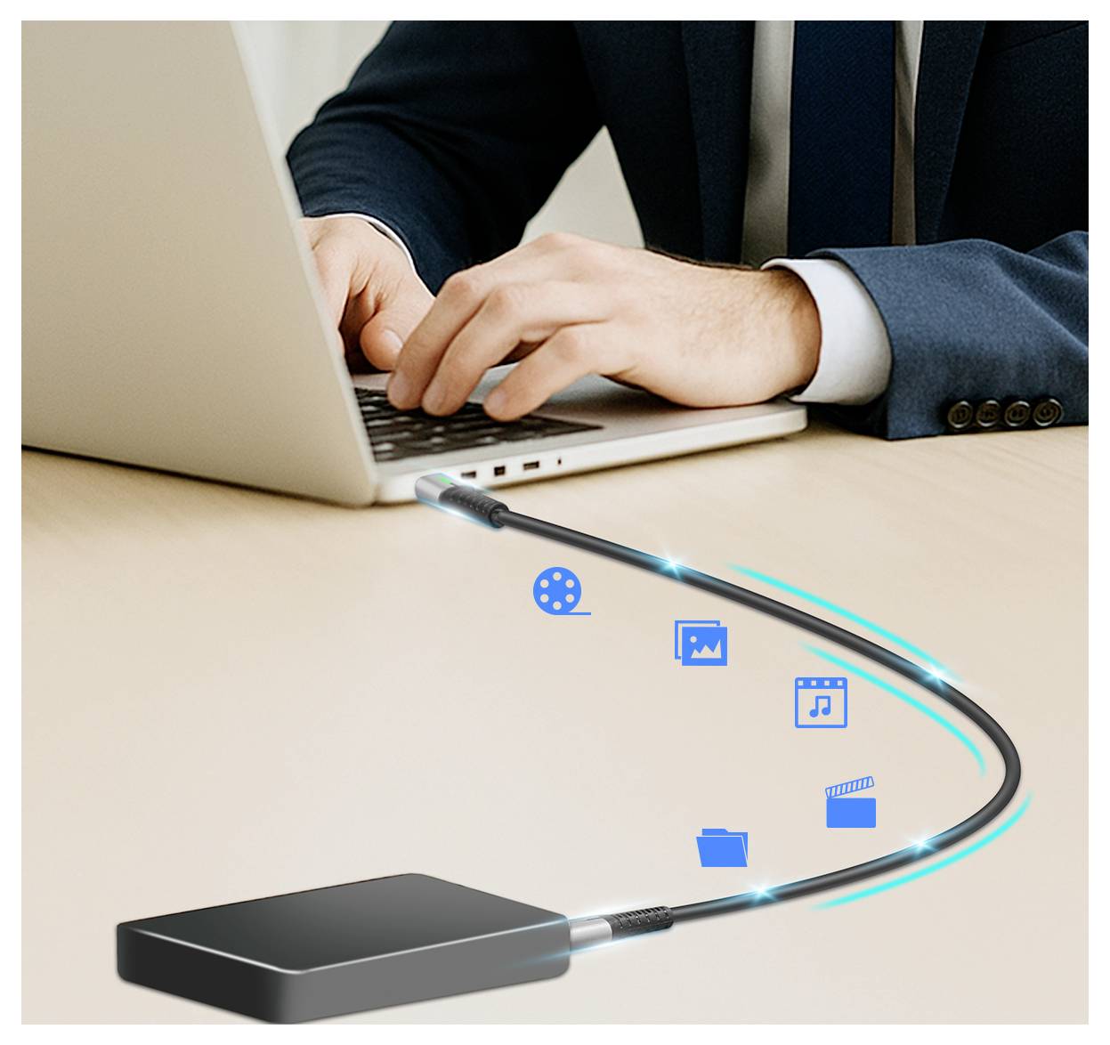 Man in a suit using a laptop at a desk, connected to an external drive with icons representing data types being transferred.