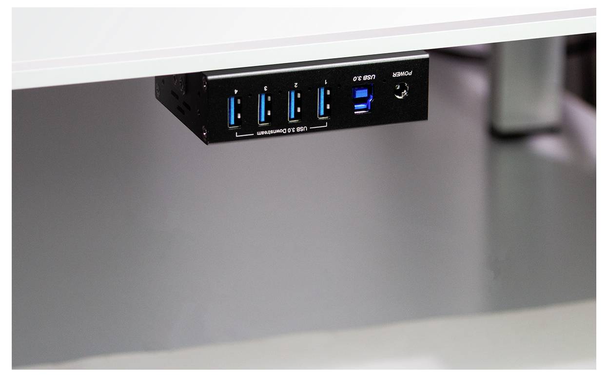 A USB hub mounted under a desk with four USB 3.0 ports and an audio jack, providing convenient access for connecting devices.