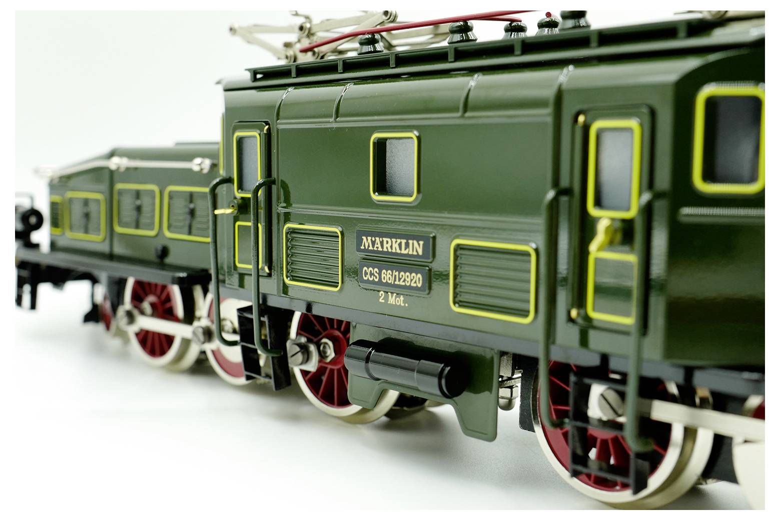 A detailed model of a vintage green Märklin locomotive with red and white wheels, showing the intricate design and branding details.