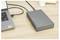A laptop is connected to an external hard drive on a wooden desk, suggesting data transfer or backup activity.