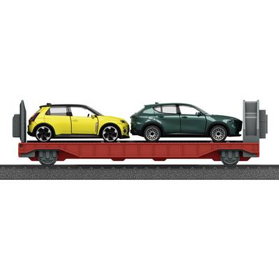Two cars, one yellow and one green, are loaded on a flatbed railcar with a red base, viewed from the side on railroad tracks.