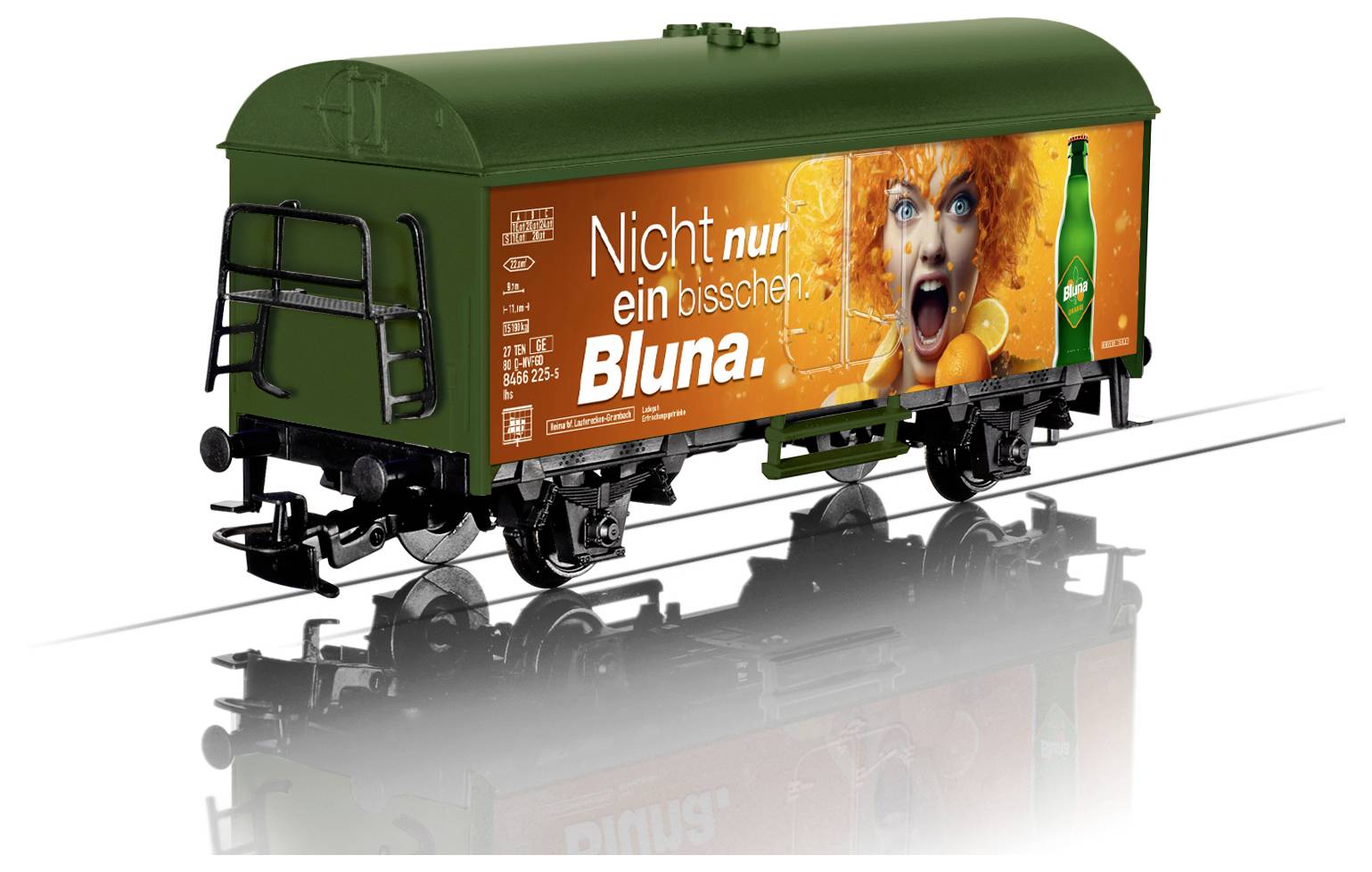 A green train car with an orange advertisement showing an excited person holding citrus fruits. The text reads 'Nicht nur ein bisschen Bluna.'