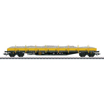 'Side view of a yellow and black train cargo wagon loaded with gravel, positioned on a railway track.'