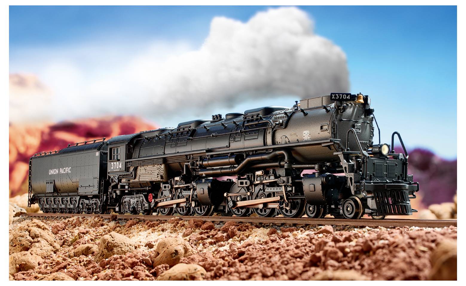 A model train designed with detailed black engine and carriage travels along a track through a desert landscape with rocky terrain.