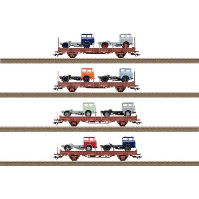 Model train flatcars carrying vintage trucks in various colors, displayed in five horizontal rows on parallel tracks.