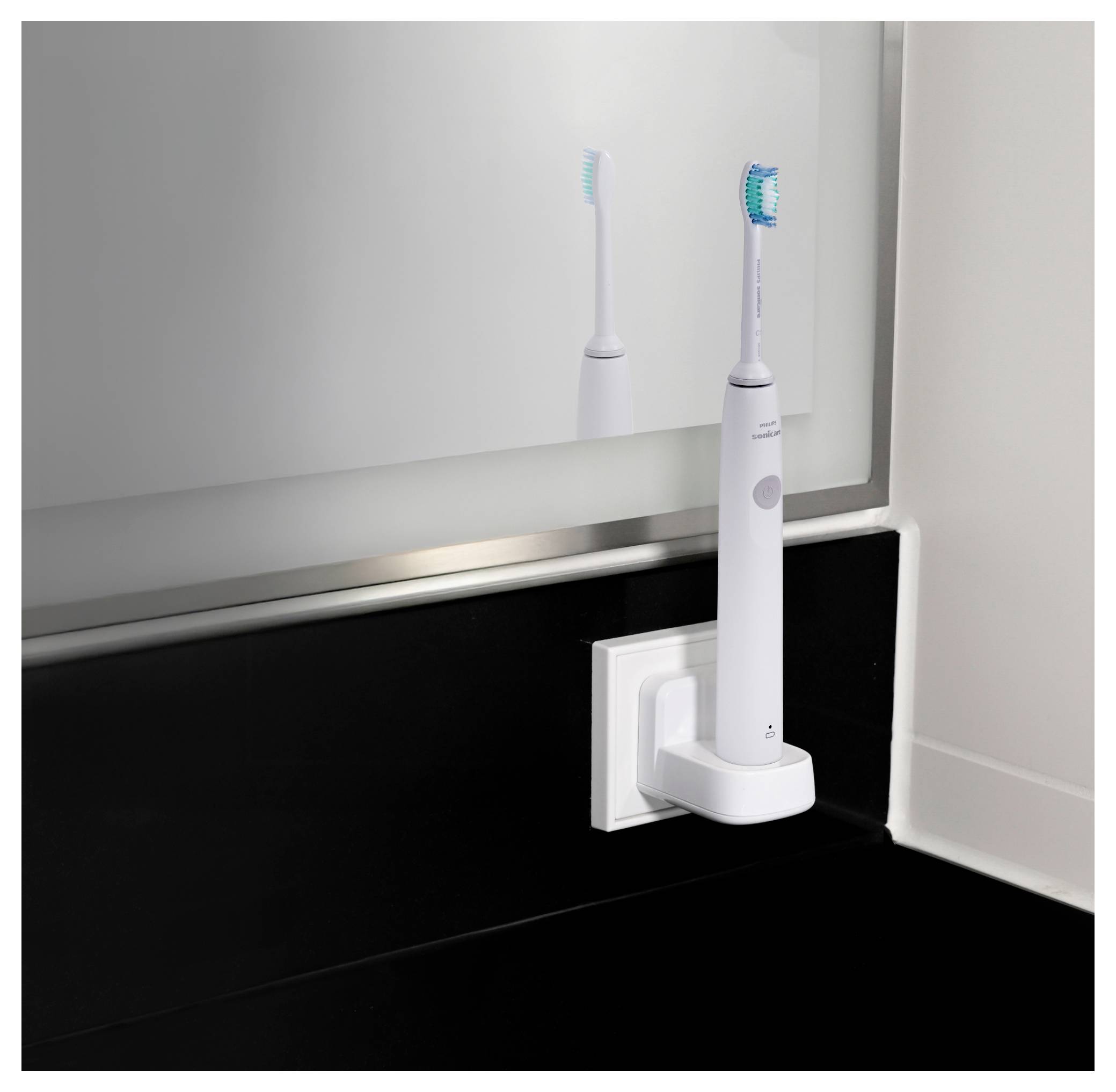An electric toothbrush mounted on a black wall in a modern bathroom setting, with its reflection visible in a mirror.
