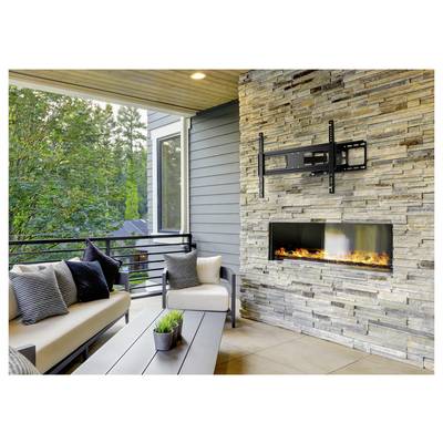 Outdoor patio with stone fireplace, cushioned seating, and table. Greenery visible through railings enhances the cozy atmosphere.