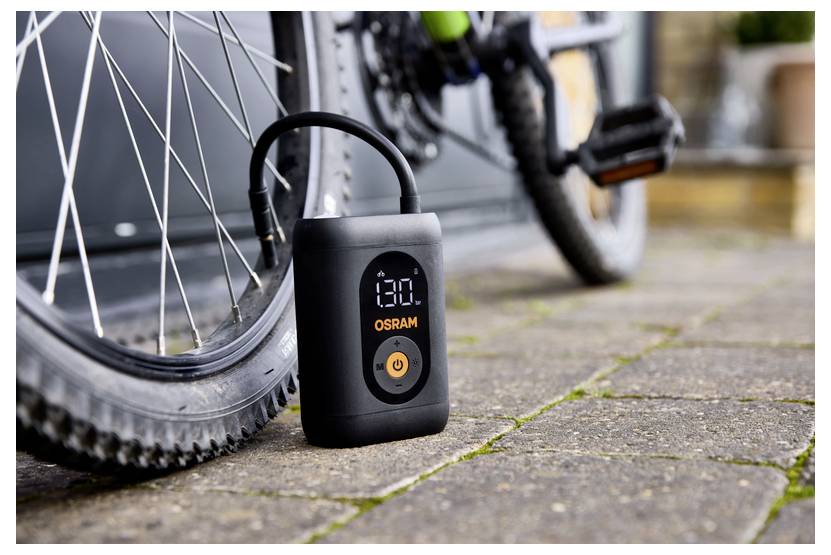 A portable air compressor is inflating a bicycle tire. The digital screen on the compressor reads '13.0'.