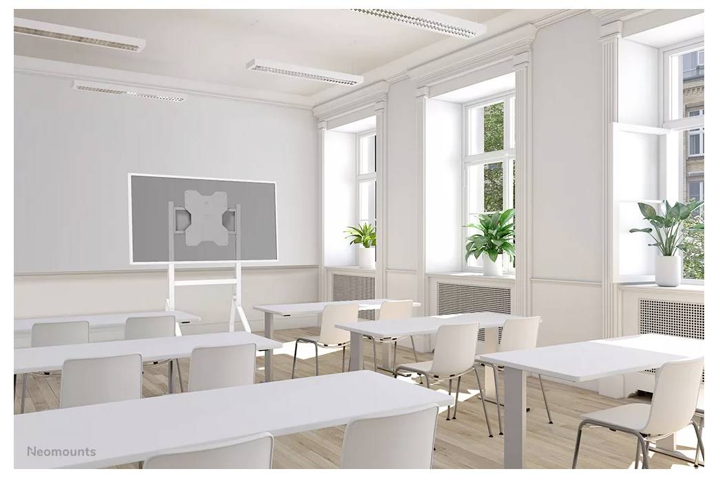 'An empty, bright classroom with rows of white desks, chairs, and a rolling whiteboard. Large windows let in natural light, and potted plants by windowsills add greenery.'