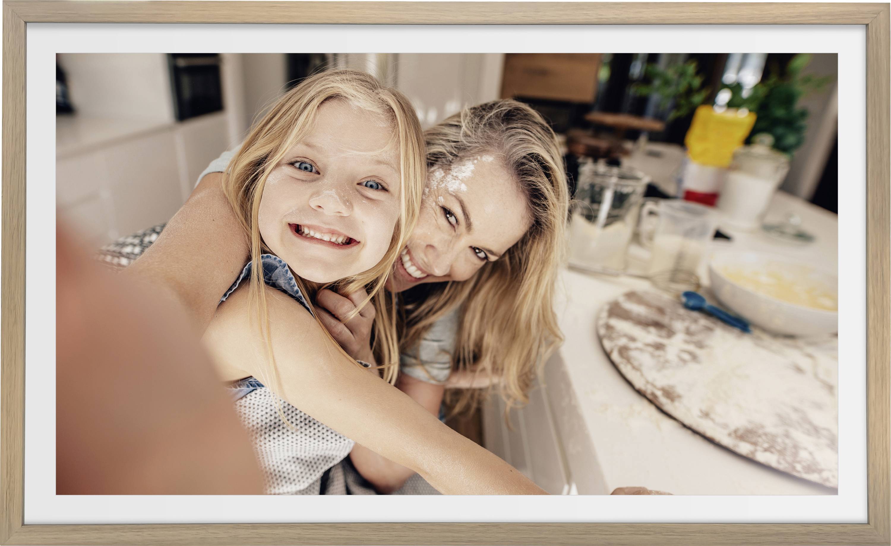 A woman and a child smile playfully in a kitchen, with flour on their faces. The counter is cluttered with baking supplies.