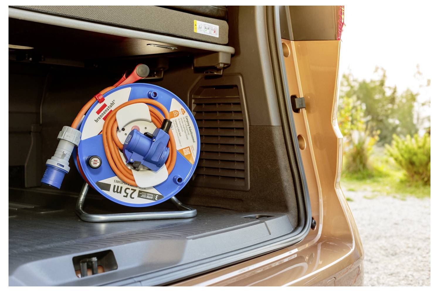 A blue and orange electrical cable reel with '25 m' printed on it rests in the back of an open vehicle, ready for use.