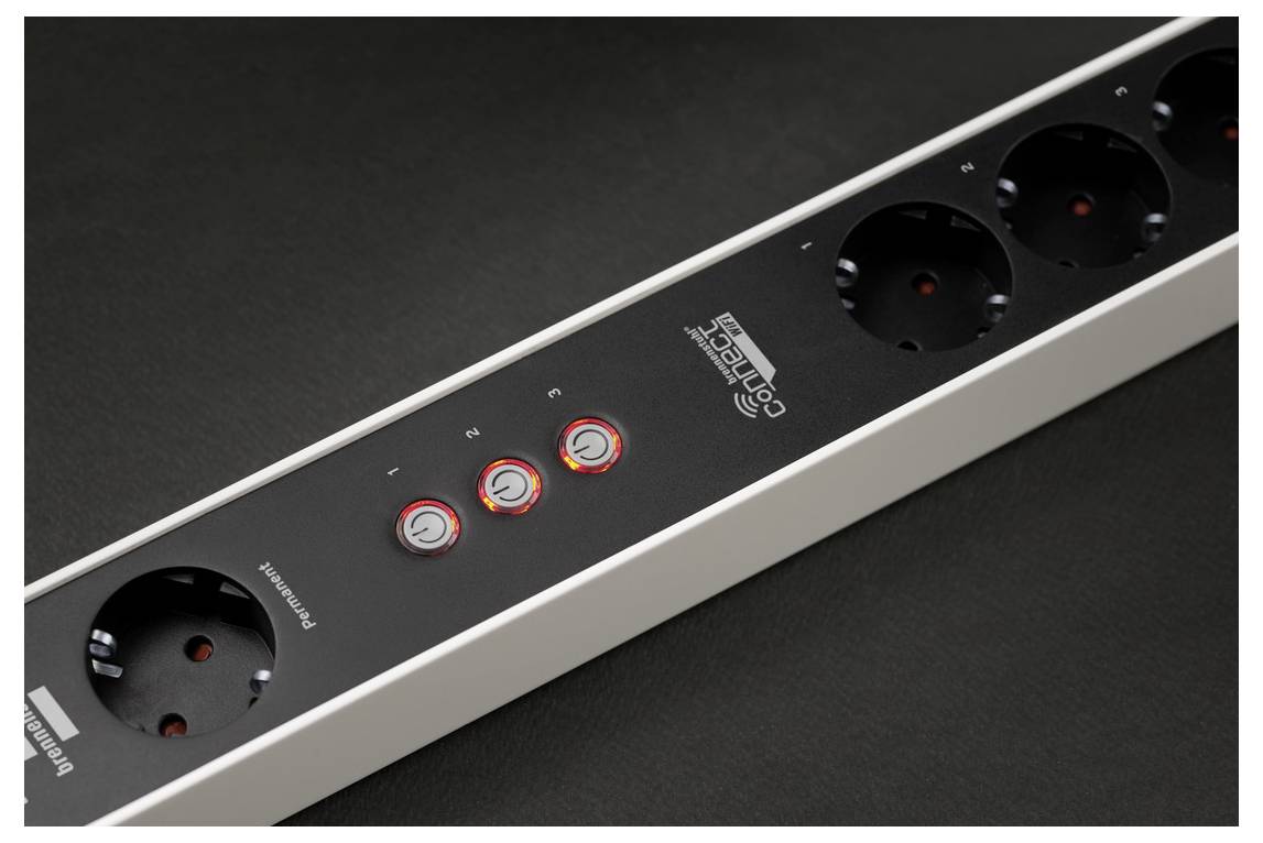 A white power strip with multiple sockets and control buttons, placed on a dark surface.