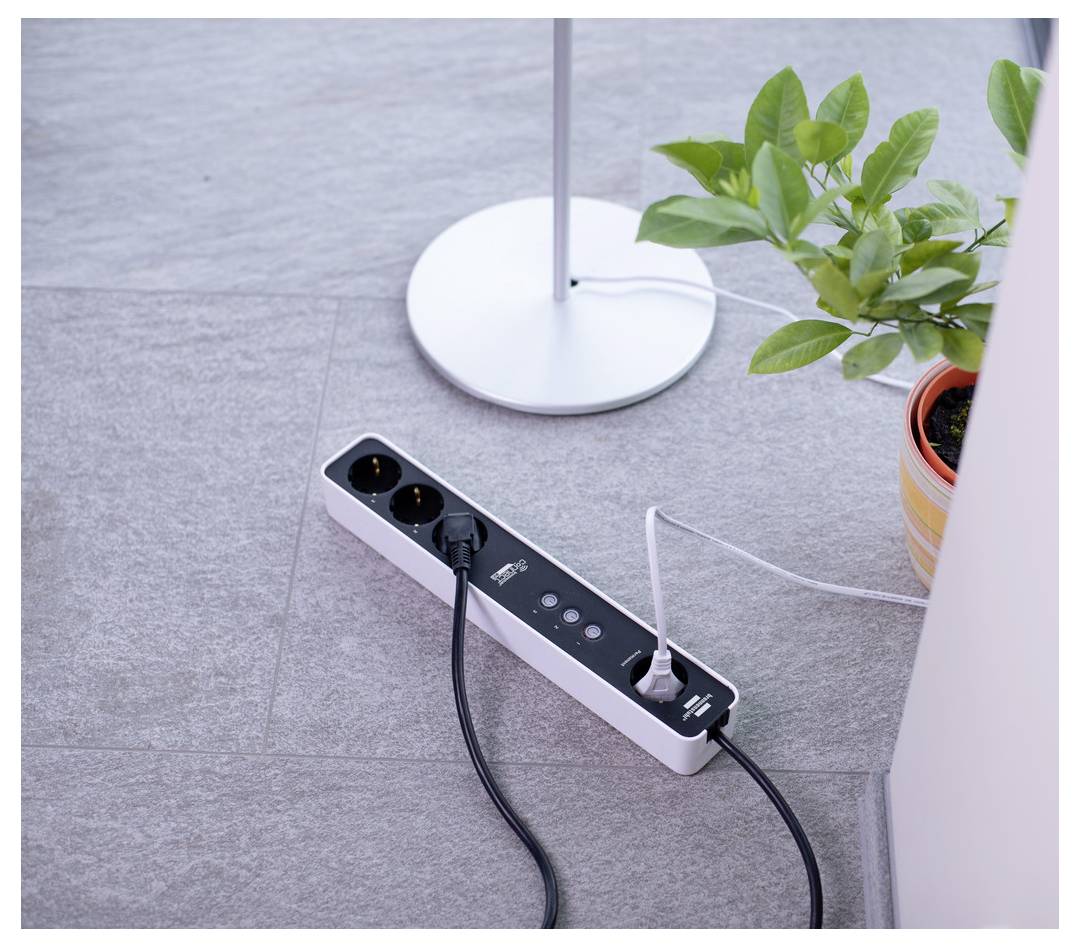 'Power strip on a tiled floor with two plugs connected, next to a white lamp base and a potted plant.'