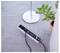 'Power strip on a tiled floor with two plugs connected, next to a white lamp base and a potted plant.'
