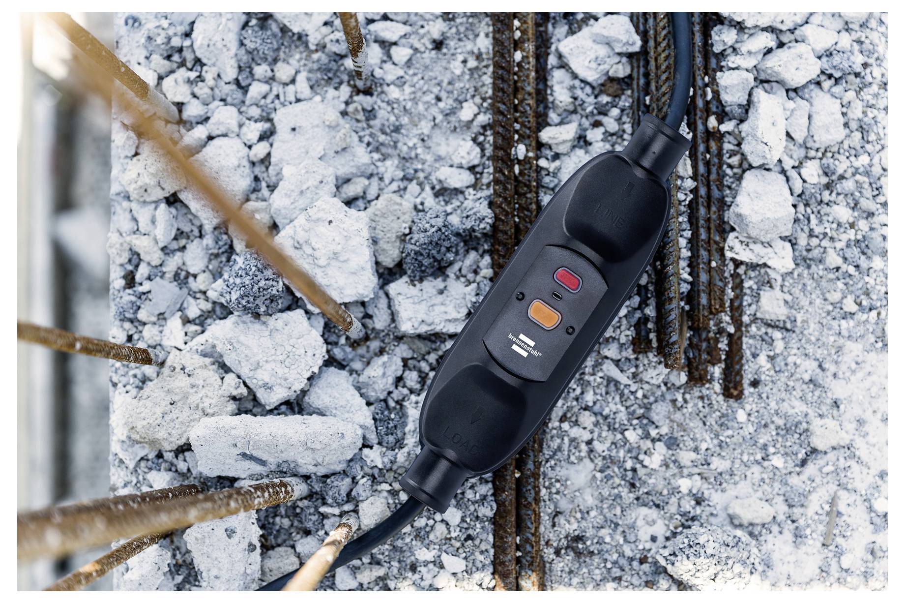 A circuit breaker on a construction site lies on rubble with rusty rebar, showing safety mechanisms in progress during building.