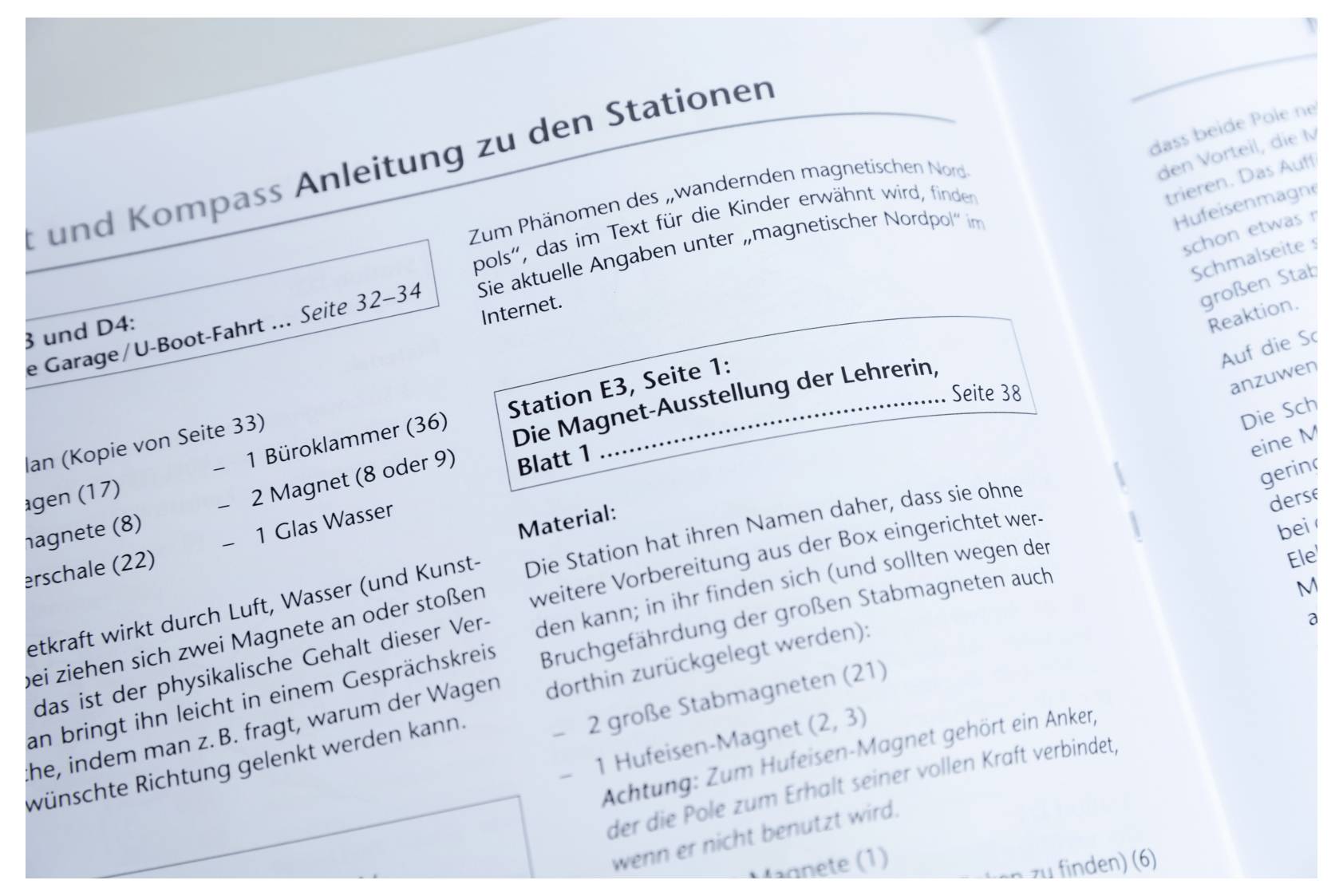 The image shows an open book in German with sections titled 'Station E3, Seite 1: Die Magnet-Ausstellung der Lehrerin, Blatt 1', listing materials such as magnets and boxes.