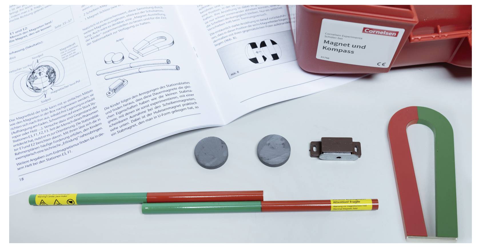 Magnet kit with open manual showing illustrations, labeled 'Magnet und Kompass'. Includes magnets, metal pieces, and compass elements.