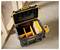 A black and yellow tool box with open compartments is sitting on a concrete floor, next to a cordless drill, in a construction area.