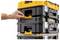 A hand opens a latch on a stack of interlocking black and yellow toolboxes, demonstrating their modular storage design.