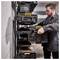 A person organizes sturdy black and yellow toolboxes on a wall-mounted shelf in a garage, emphasizing efficient storage.