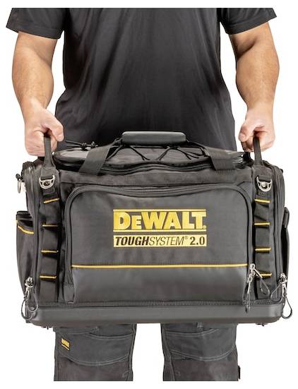 A person holds a large, black tool bag with the 'DEWALT TOUGHSYSTEM 2.0' logo. The bag has multiple pockets and sturdy handles.
