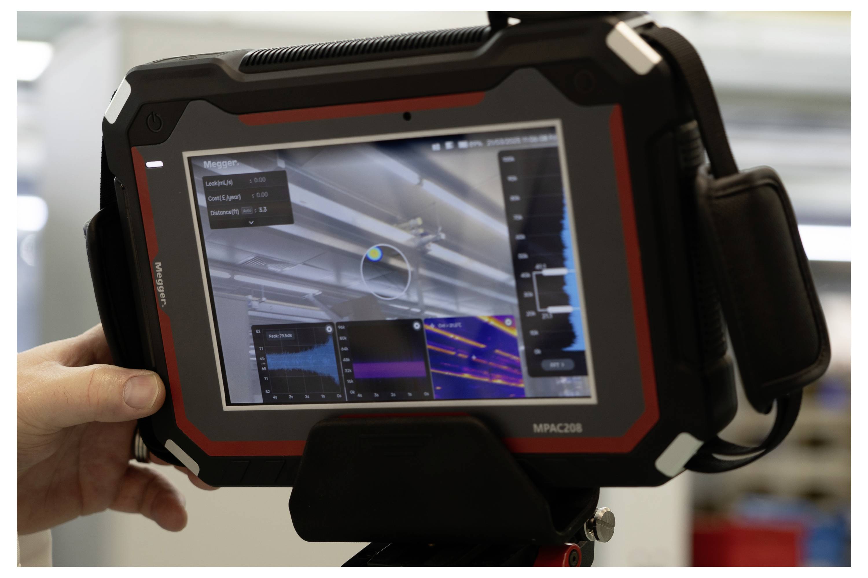 Hand holding an industrial tablet displaying complex data charts and a color-coded diagnostic interface, used for equipment analysis.