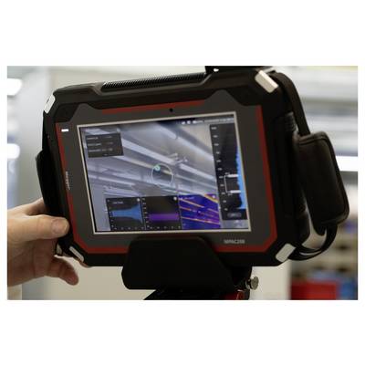 Hand holding an industrial tablet displaying complex data charts and a color-coded diagnostic interface, used for equipment analysis.