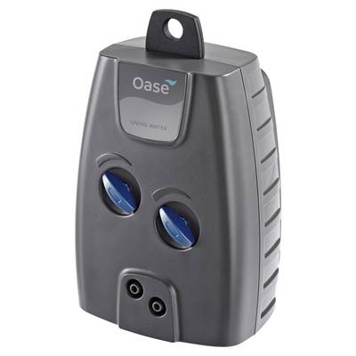 Gray Oase Living Water device with top hanging loop, two blue adjustment dials, and two outlet ports, shown front view.