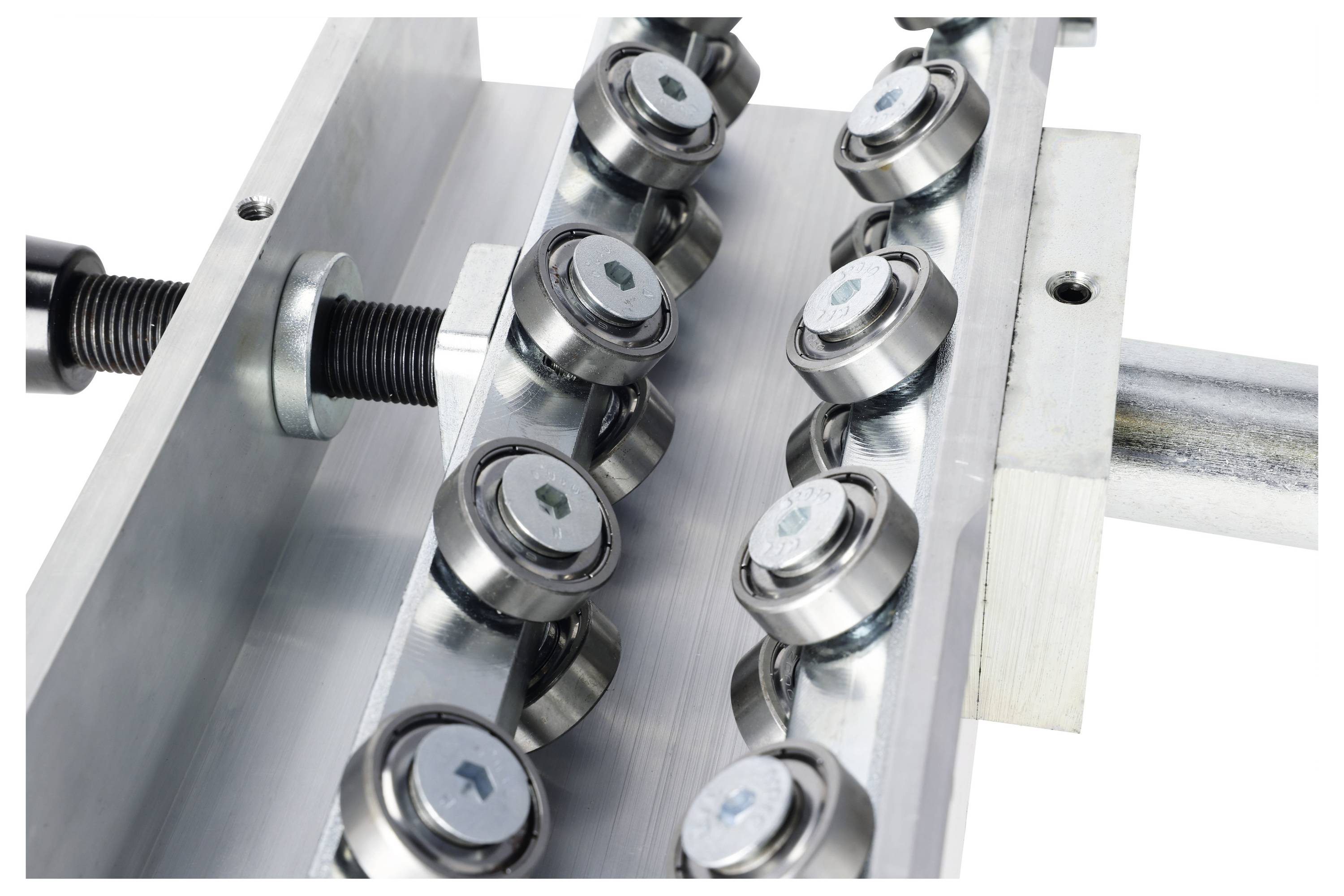 A close-up of a metal rail bearing system with multiple ball bearings aligned along two rails, part of industrial machinery for mechanical movement.