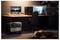 'A dimly lit room with a desk, computer, aquarium, and sleeping dog; a wheeled device labeled "Heirloom" is on the floor nearby.'