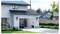 'A garage with an electric car plugged into a wall charger, surrounded by a suburban neighborhood with green lawns and trees.'