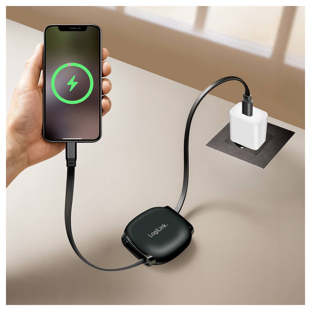 A person charges a smartphone using a power bank connected to a wall plug. The phone screen shows a green charging symbol.