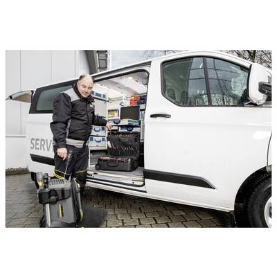 A technician in work attire stands beside an open van filled with tools and equipment, holding a portable device, ready for service.