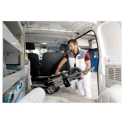 A man in work attire loads a saw into a van, suggesting he's preparing for a job or transporting tools. Shelves inside the van hold various equipment.