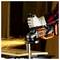 'A person wearing gloves uses a Black+Decker angle grinder, creating sparks, to cut a metal pipe in a workshop setting.'