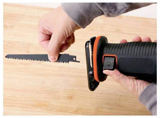 'A person attaches a saw blade to a reciprocating saw on a wooden surface, highlighting the tool's easy blade installation feature.'