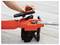 A person is adjusting the cap on an orange chainsaw, which is lying on a wooden surface.