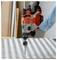 A person wearing gloves uses a cordless power drill to work on a checkered metal surface.