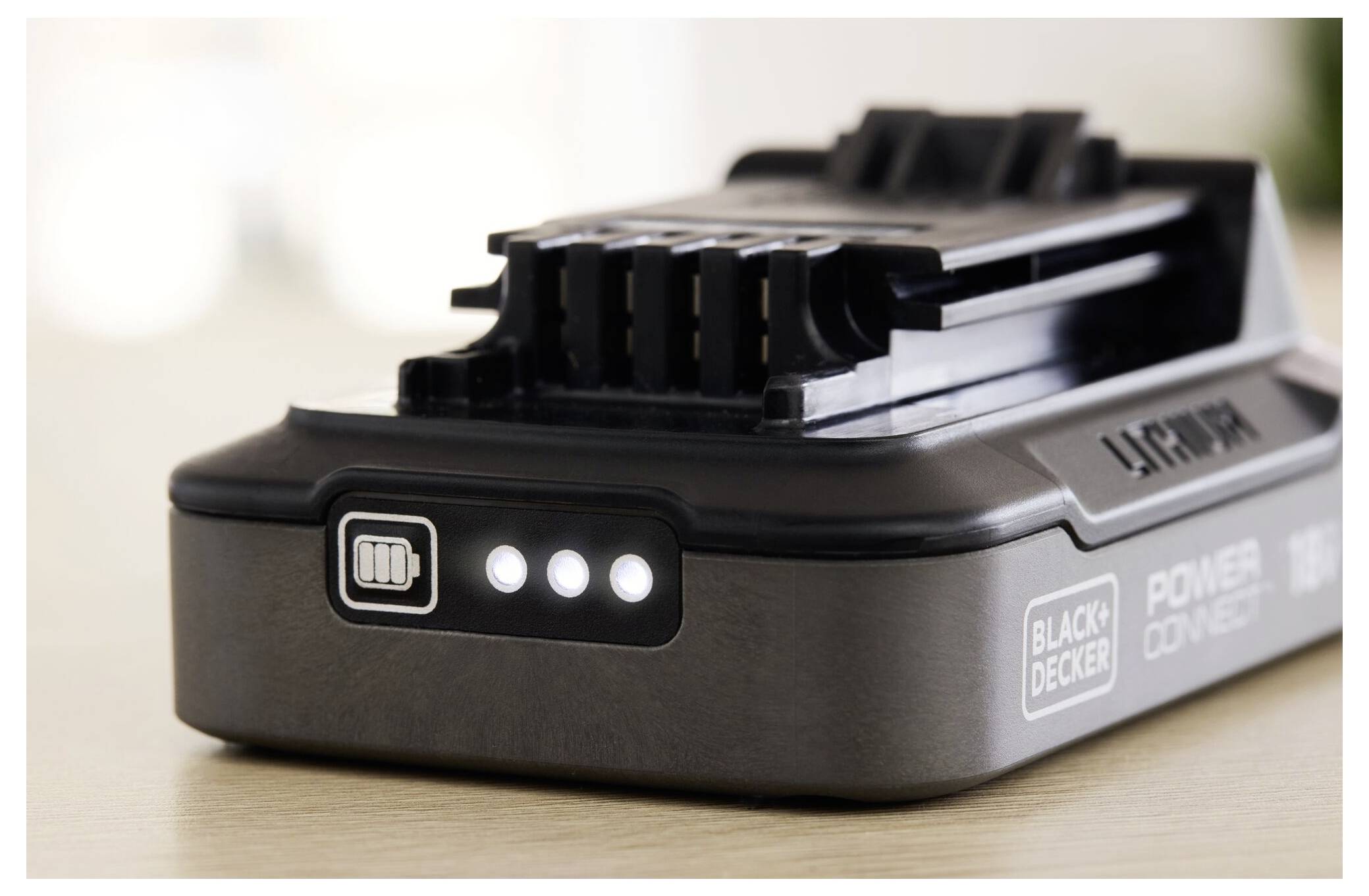 A close-up of a rechargeable battery with three indicator lights on, showing it's charged. The brand name is visible on the side.