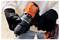 A person wearing black gloves holds an orange and black electric drill, showing the brand 'BLACK+DECKER', highlighting its grip and design.