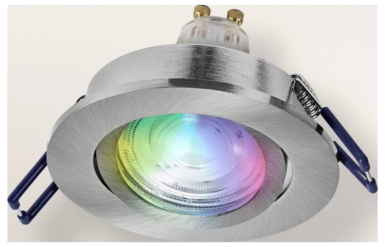 A metallic recessed ceiling light with a circular design, emitting a colorful glow in blue, green, and pink hues from its glass lens.