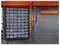 A wall-mounted black organizer with multiple transparent drawers beside a pegboard holding red and blue tools on an orange shelf.
